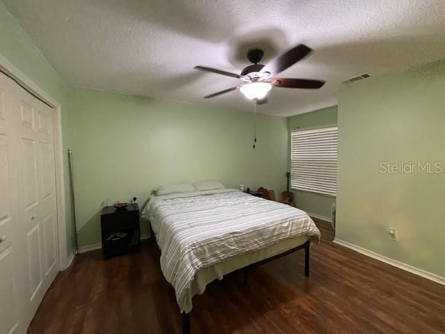 bedroom with a textured ceiling, dark hardwood / wood-style flooring, a closet, and ceiling fan