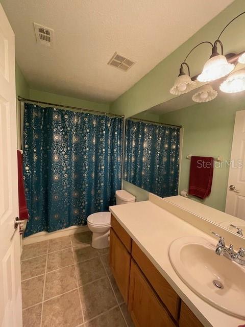 bathroom featuring tile flooring, vanity with extensive cabinet space, and toilet