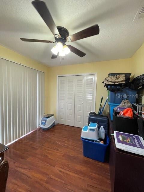 interior space featuring a textured ceiling, a closet, ceiling fan, and dark wood-type flooring