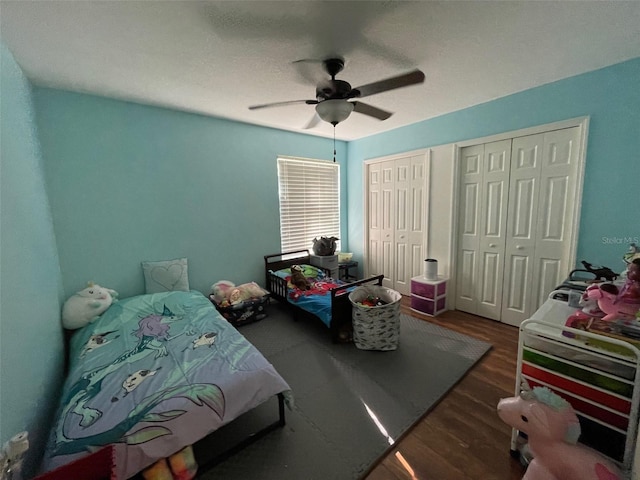 bedroom featuring two closets, ceiling fan, and dark hardwood / wood-style flooring