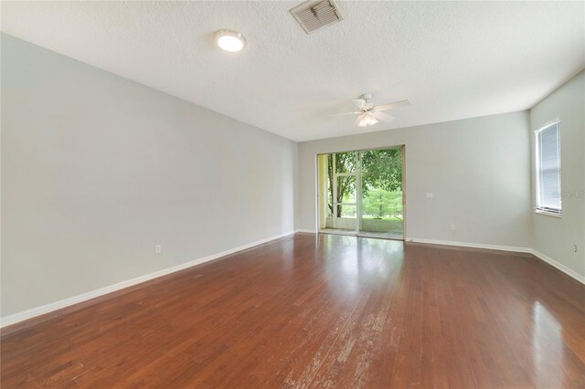 unfurnished room with a textured ceiling, ceiling fan, and dark wood-type flooring