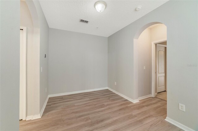 empty room with light hardwood / wood-style floors and a textured ceiling