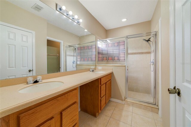 bathroom featuring dual vanity, an enclosed shower, and tile patterned flooring