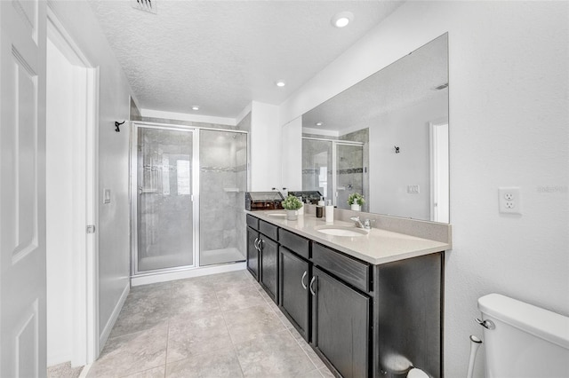 bathroom featuring toilet, oversized vanity, a textured ceiling, tile floors, and an enclosed shower