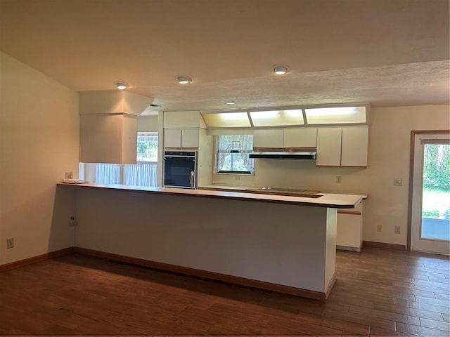 kitchen featuring dark hardwood / wood-style floors, kitchen peninsula, black appliances, and white cabinetry