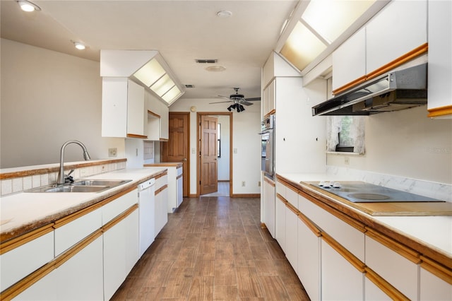 kitchen featuring sink, ceiling fan, dark wood-type flooring, wall chimney range hood, and stainless steel oven