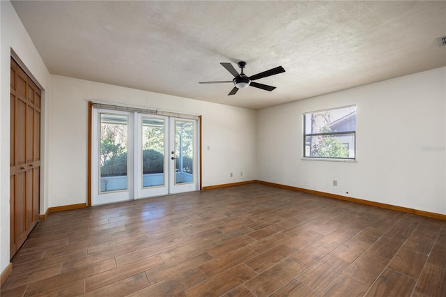 empty room featuring french doors, ceiling fan, and dark wood-type flooring