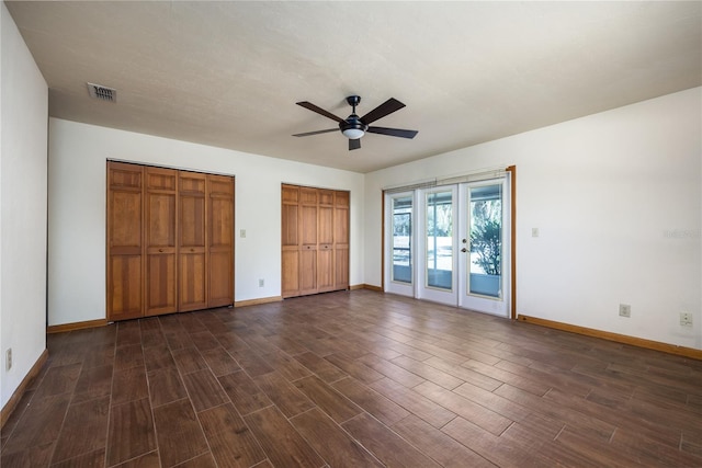 unfurnished bedroom with access to outside, multiple closets, dark hardwood / wood-style floors, and ceiling fan