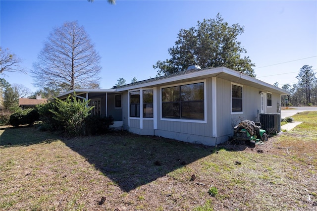 back of house featuring a lawn and central air condition unit