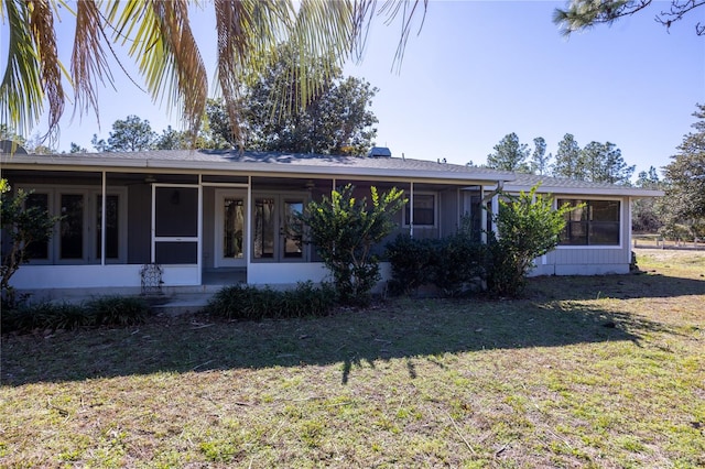 back of property with a sunroom and a lawn