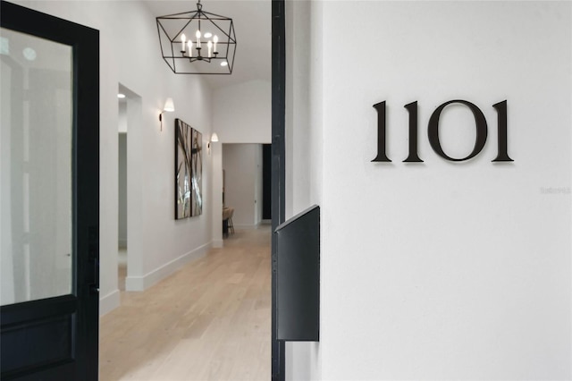 corridor with an inviting chandelier and light hardwood / wood-style flooring