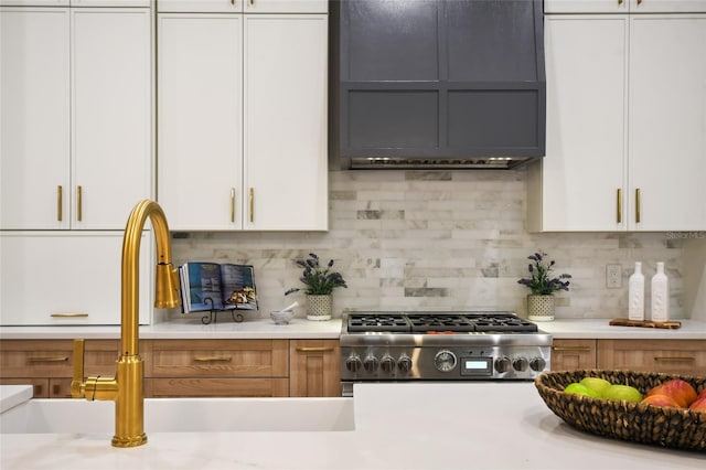 kitchen featuring backsplash, white cabinetry, sink, and stainless steel gas range