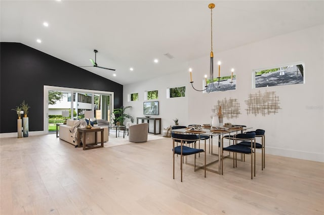 dining room featuring ceiling fan with notable chandelier, light hardwood / wood-style flooring, and vaulted ceiling