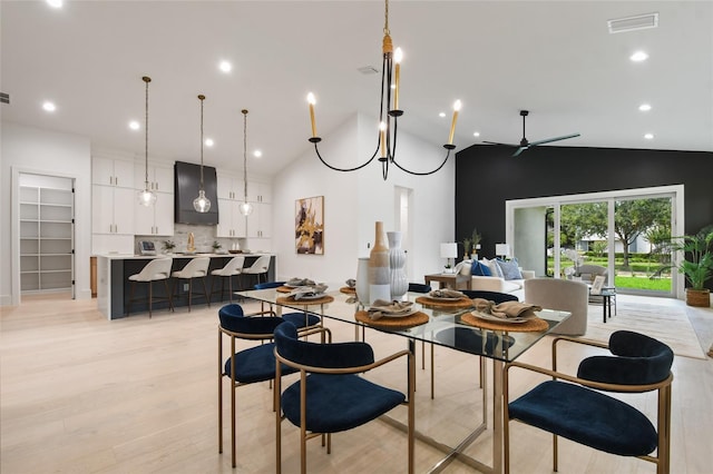 dining area featuring high vaulted ceiling, light hardwood / wood-style floors, and ceiling fan with notable chandelier