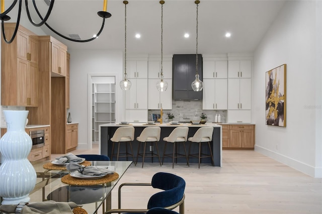 kitchen featuring a center island, pendant lighting, decorative backsplash, white cabinets, and light wood-type flooring