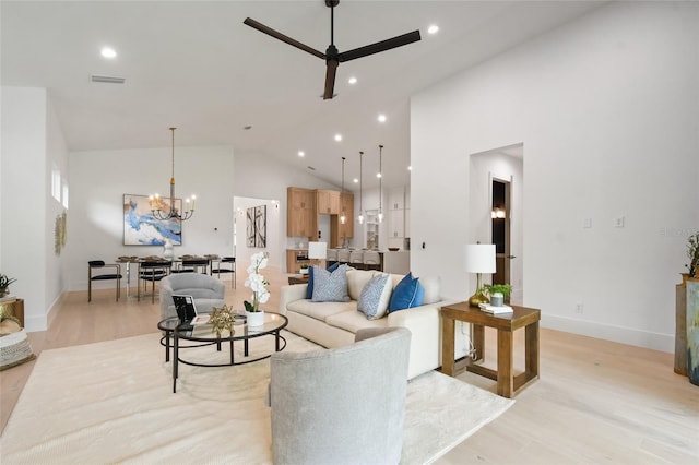 living room featuring ceiling fan with notable chandelier, light hardwood / wood-style floors, and high vaulted ceiling