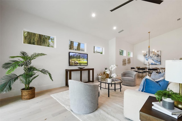 living room with lofted ceiling, plenty of natural light, light hardwood / wood-style floors, and ceiling fan with notable chandelier