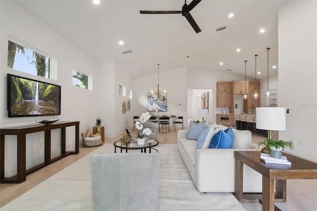 living room with high vaulted ceiling, light hardwood / wood-style floors, and ceiling fan with notable chandelier