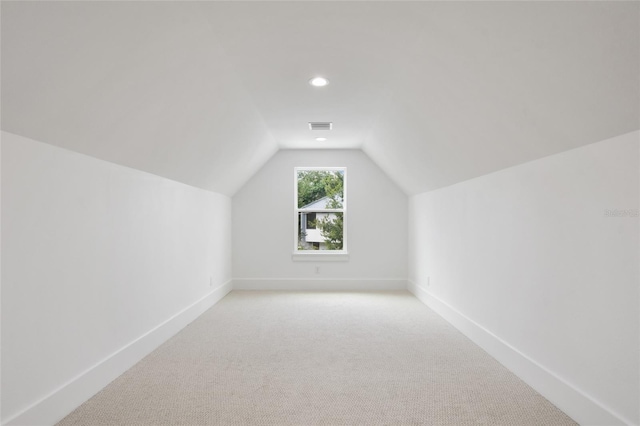 bonus room with light carpet and vaulted ceiling