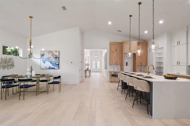 kitchen with light hardwood / wood-style flooring, white cabinets, hanging light fixtures, and lofted ceiling