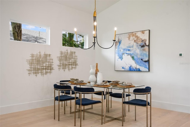 dining space with light hardwood / wood-style floors, vaulted ceiling, and an inviting chandelier