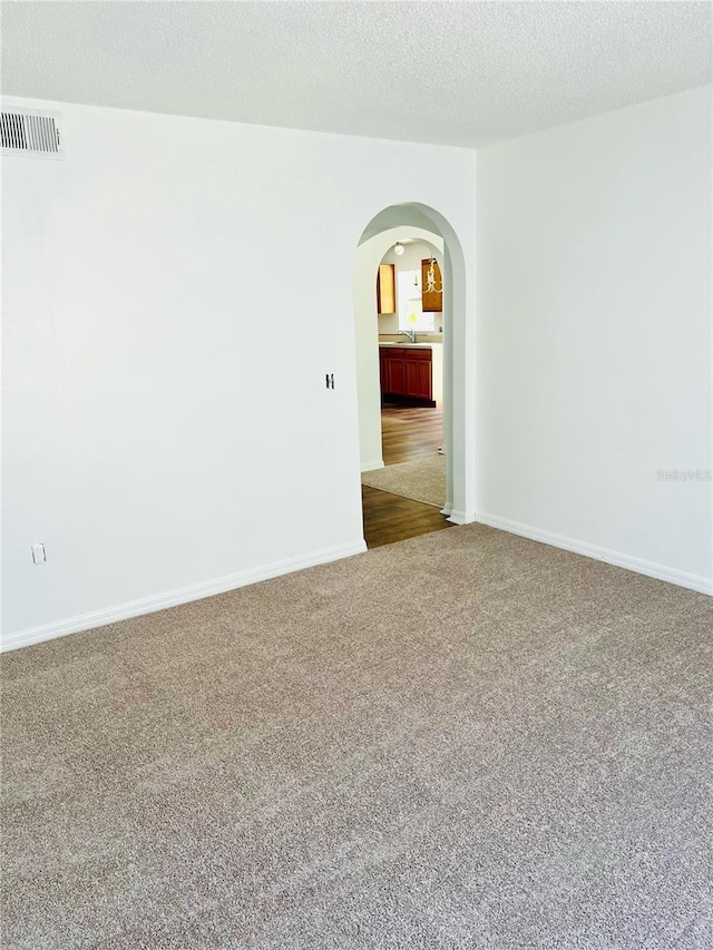 carpeted spare room featuring sink and a textured ceiling