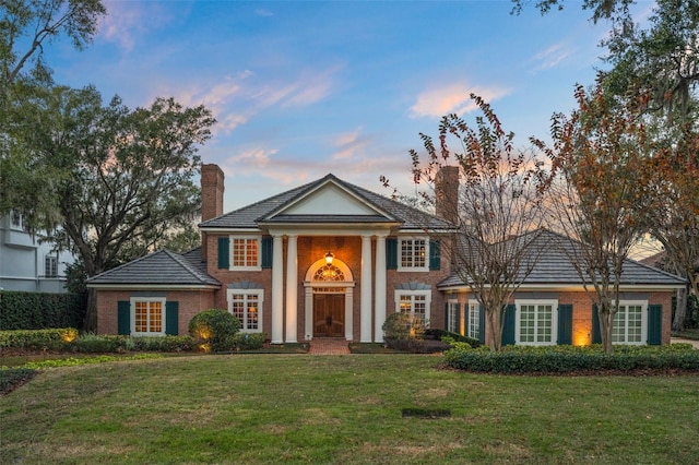 neoclassical home featuring a yard