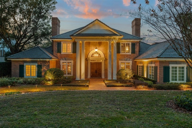 neoclassical home featuring a lawn