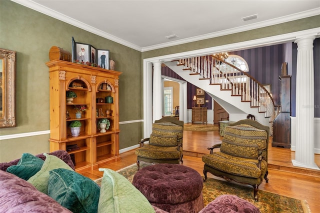 living room with light hardwood / wood-style floors, decorative columns, a notable chandelier, and ornamental molding