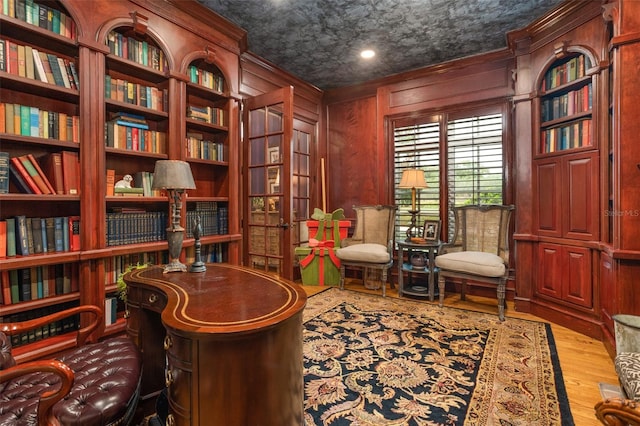 office featuring hardwood / wood-style floors, wood walls, and ornamental molding