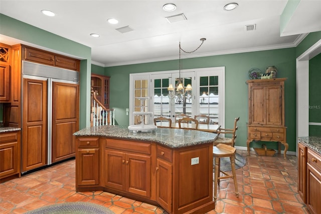 kitchen featuring a kitchen island, hanging light fixtures, a notable chandelier, and paneled built in refrigerator