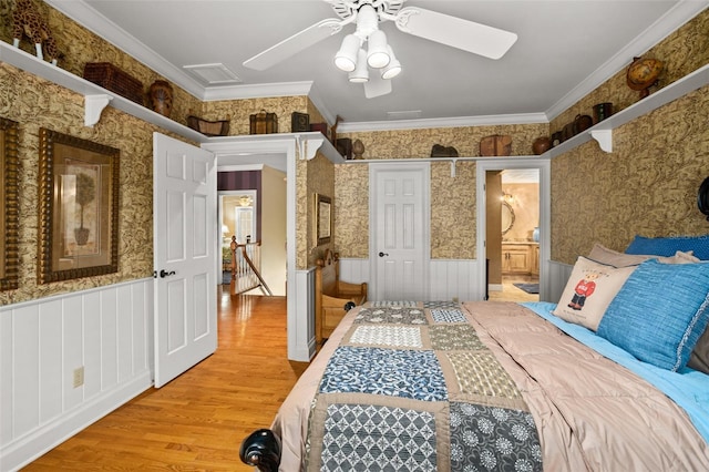 bedroom featuring ornamental molding, ceiling fan, ensuite bathroom, and light wood-type flooring