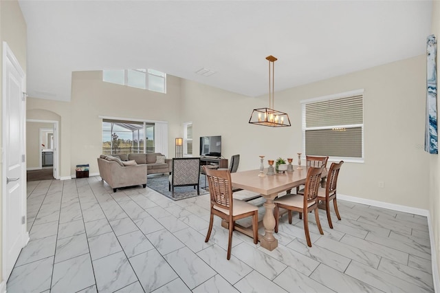 tiled dining room with a chandelier and a high ceiling