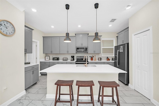 kitchen with a kitchen bar, pendant lighting, stainless steel appliances, and a center island with sink