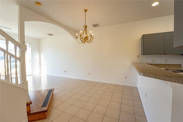 unfurnished dining area featuring stairs, light tile patterned floors, arched walkways, and visible vents