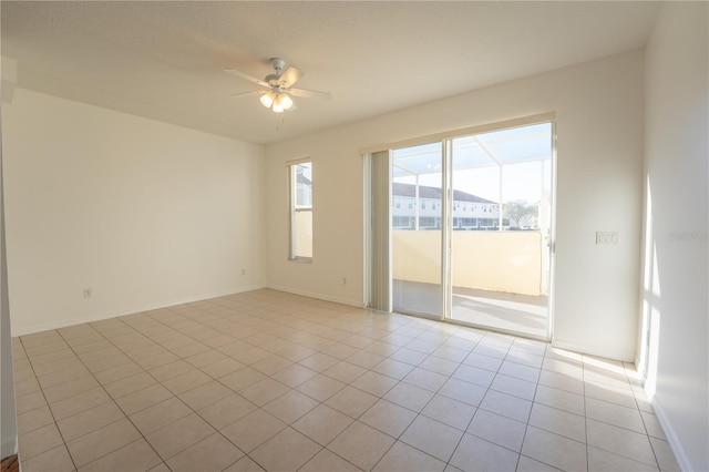 spare room with light tile patterned floors, a ceiling fan, and baseboards