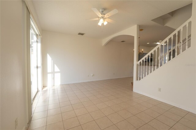 spare room with light tile patterned floors, visible vents, stairway, baseboards, and ceiling fan with notable chandelier