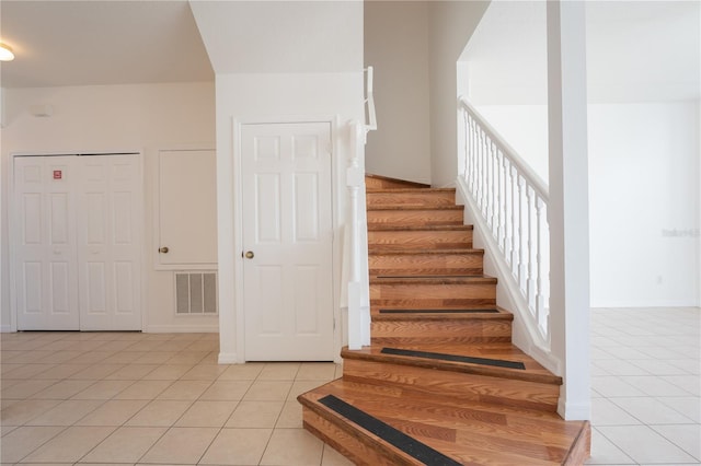 staircase featuring baseboards, visible vents, and tile patterned floors