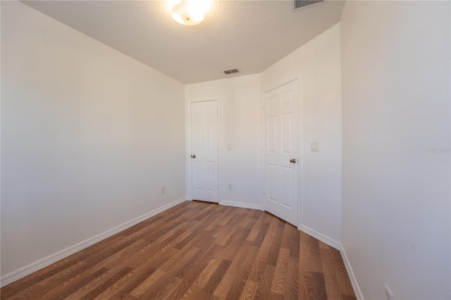 spare room with visible vents, dark wood finished floors, a textured ceiling, and baseboards