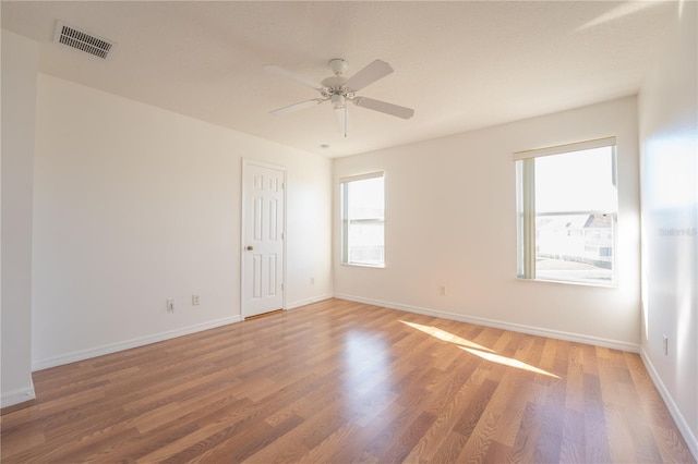 spare room with ceiling fan, wood finished floors, visible vents, and baseboards