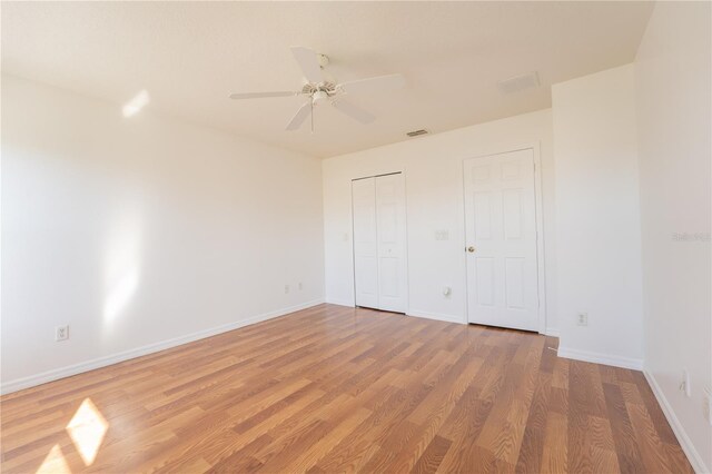 unfurnished bedroom with baseboards, visible vents, ceiling fan, wood finished floors, and a closet