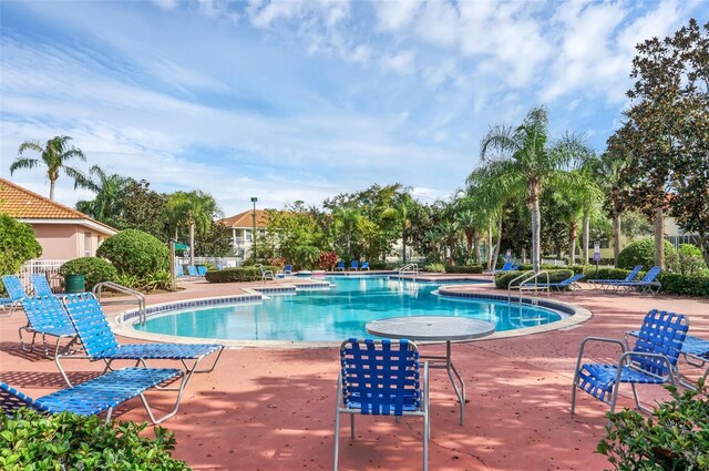 community pool with a patio area and a hot tub