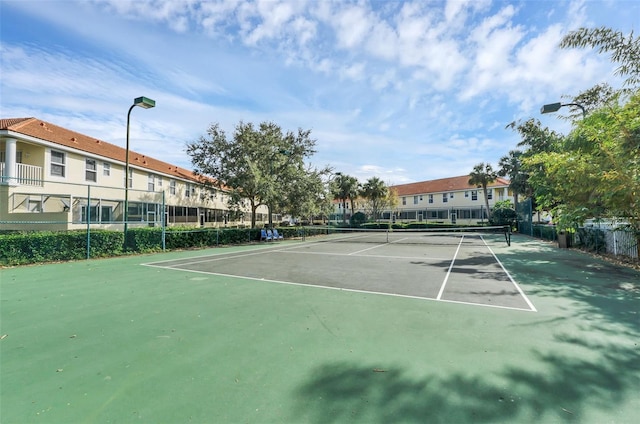 view of tennis court featuring fence and a residential view