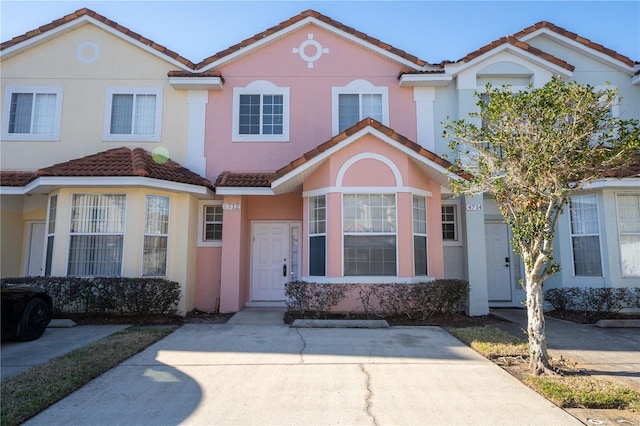 townhome / multi-family property with a tiled roof and stucco siding