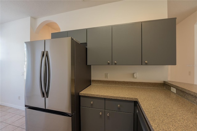 kitchen featuring freestanding refrigerator, dark countertops, gray cabinetry, and light tile patterned floors