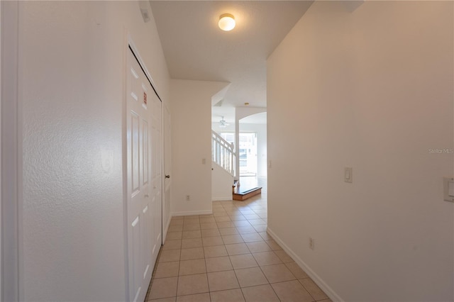 hallway with stairway, baseboards, and light tile patterned floors