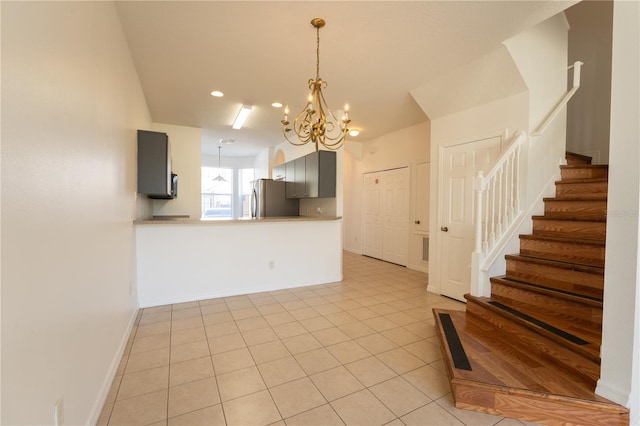 interior space with a chandelier, light tile patterned floors, a peninsula, light countertops, and freestanding refrigerator