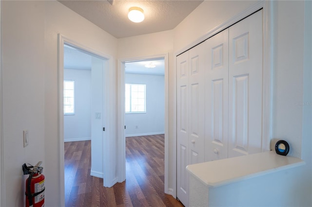 corridor with baseboards, dark wood finished floors, and a textured ceiling