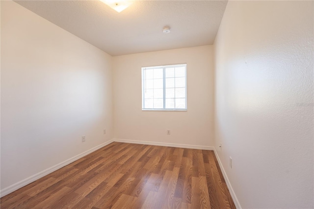 unfurnished room with dark wood-type flooring and baseboards