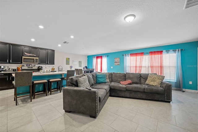 living room with a textured ceiling and light tile floors